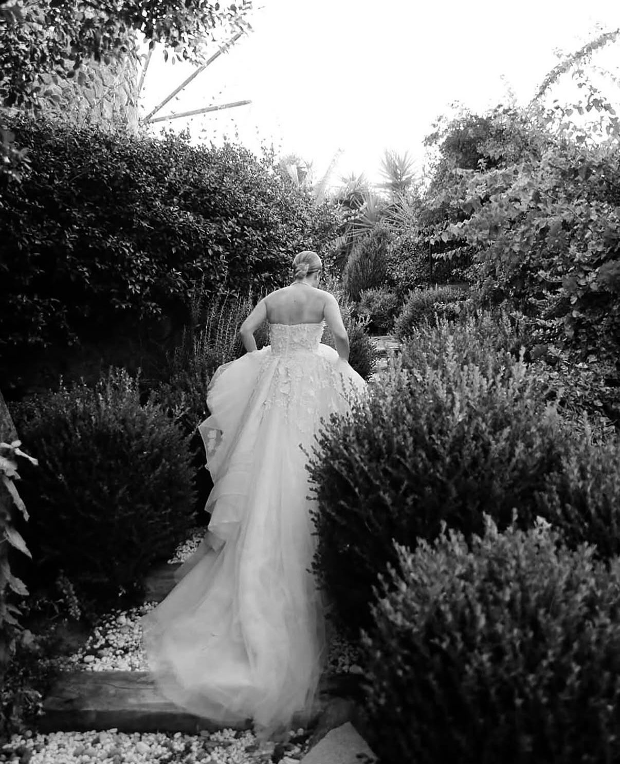 Bride walking through the garden — black and white